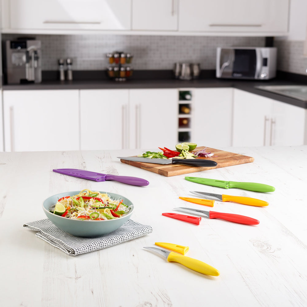 The Zyliss 6 Piece Knife Set includes six kitchen knives with color-coded handles—yellow, orange, red, green, purple, and black—each with a matching sheath for safe food prep. Handles are arranged from smallest to largest on a light background.