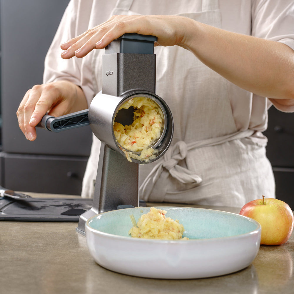 The Zyliss Universal Drum Gourmet is a stainless steel grating attachment with sharp rectangular holes, a gray plastic cap and axle, shown isolated on a light background.