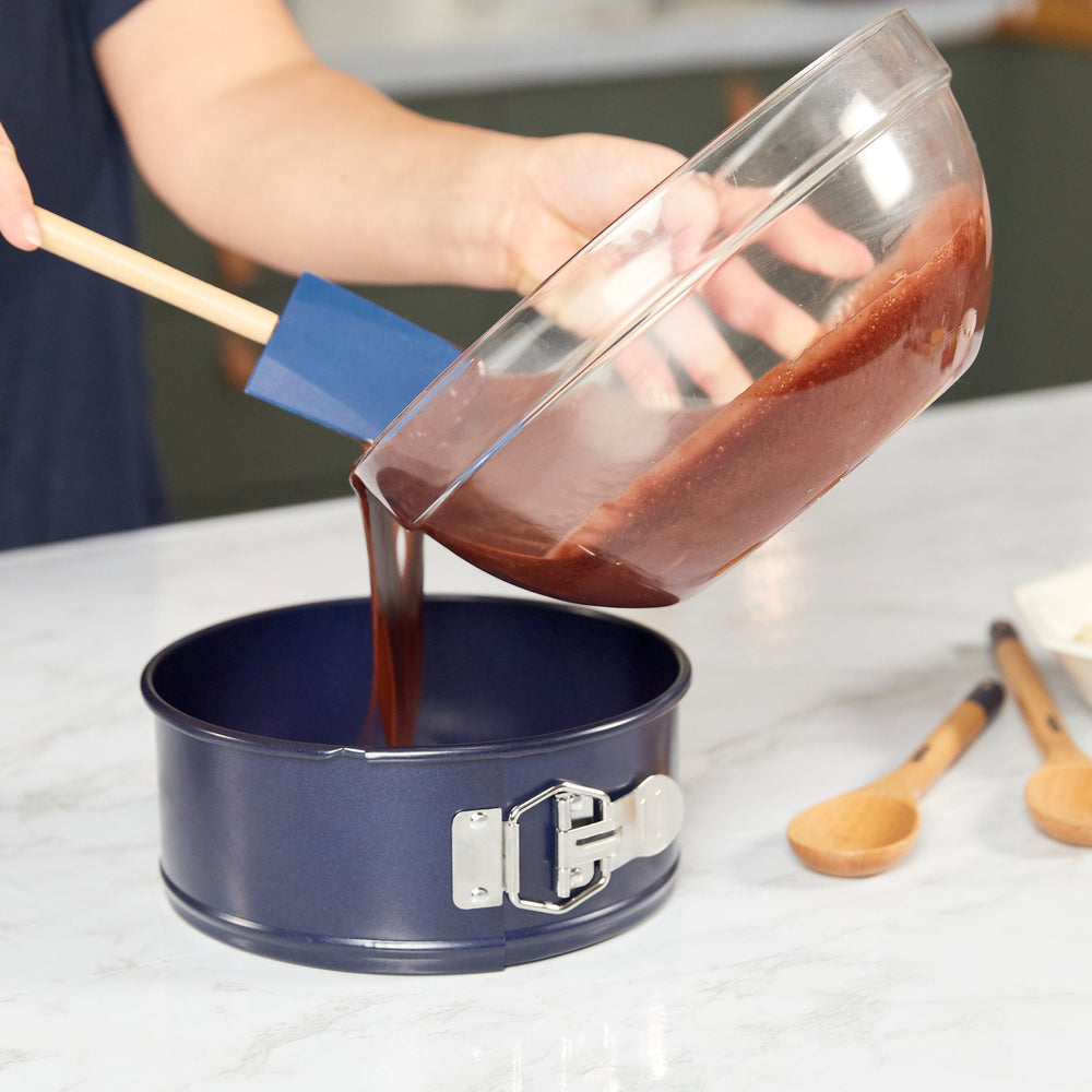 The Zyliss Durable Non-Stick Springform Cake Pan features a round black design with a silver latch, ideal for baking delicate cheesecakes, and is shown against a plain light background.