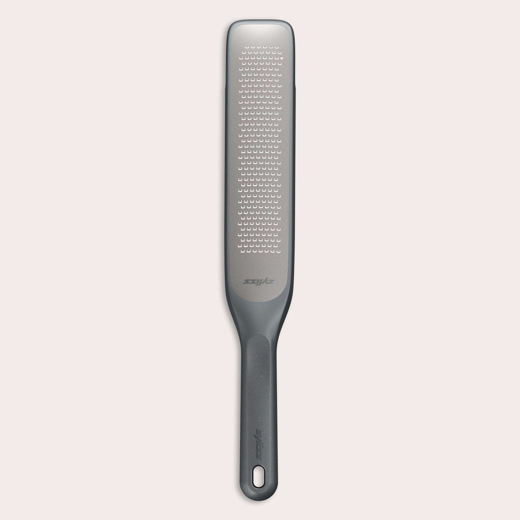 The Zyliss Rasp Grater is a long, rectangular foot file with a gray handle and textured metal surface for removing calluses and dead skin. The handle features a hanging hole for easy storage.