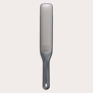 The Zyliss Rasp Grater is a long, rectangular foot file with a gray handle and textured metal surface for removing calluses and dead skin. The handle features a hanging hole for easy storage. 