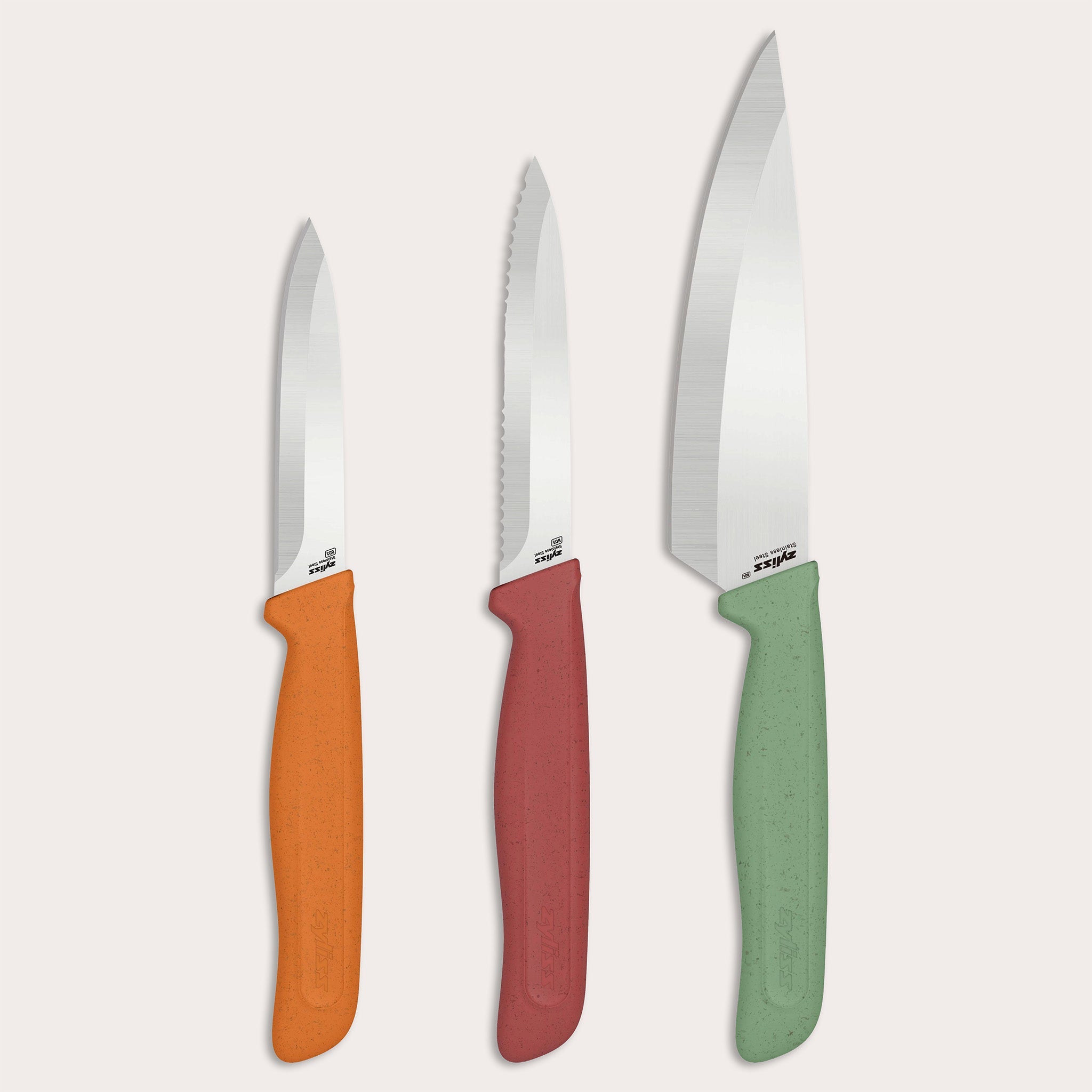 The Zyliss Classic 3-Piece Paring & Utility Knife Set features stainless steel knives with colorful orange, red, and green handles. Upright against a light background, the center utility knife is serrated; the paring knives have smooth blades.