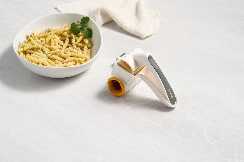 A bowl of pasta with a Zyliss Classic Cheese Grater, a knife, and a fork